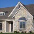 The exterior walls of a home outfitted with Grey Buff Chateau stone veneer from Halquist's Castlestone Collection.